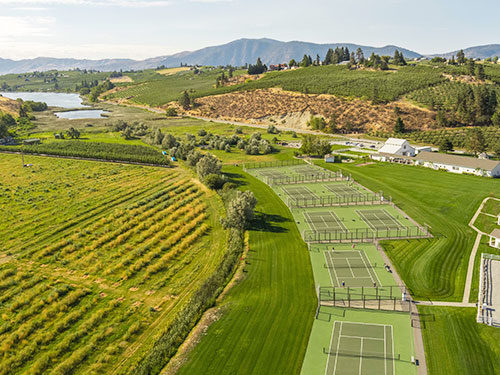 Aerial photo of Harmony Meadows. Grass, tennis courts, resort, orchards